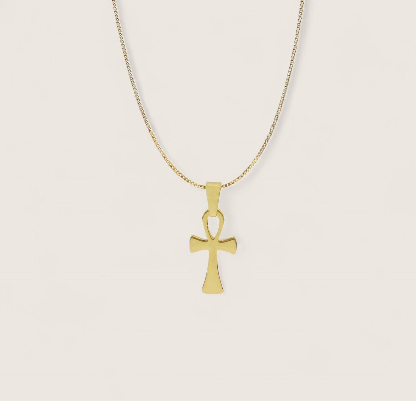 Gold cross pendant necklace on a light beige background