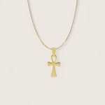 Gold cross pendant necklace on a light beige background