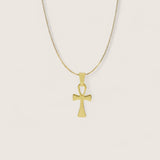 Gold cross pendant necklace on a light beige background