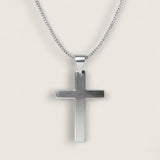 Silver cross pendant on a chain against a light gray background