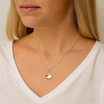 Necklace with a pendant worn by a person against a neutral background