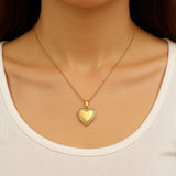Gold heart-shaped necklace on a person wearing a white top