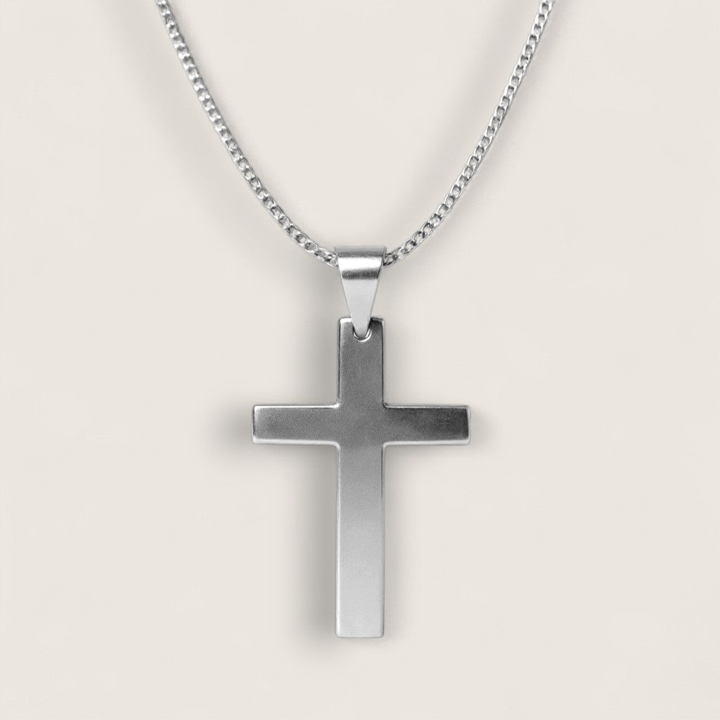Silver cross pendant on a chain against a light gray background
