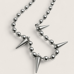 Necklace with silver beads and spike-like pendants on a light gray background