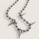 Necklace with silver beads and spike-like pendants on a light gray background