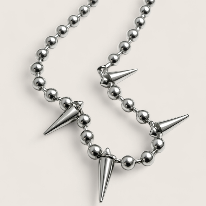 Necklace with silver beads and spike-like pendants on a light gray background