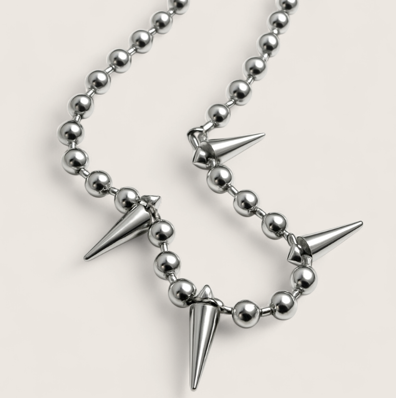 Necklace with silver beads and spike-like pendants on a light gray background