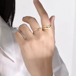 Hand wearing two gold rings on a white background