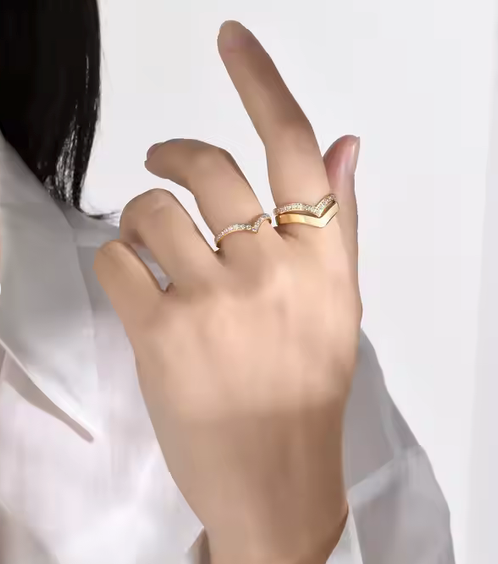 Hand wearing two gold rings on a white background