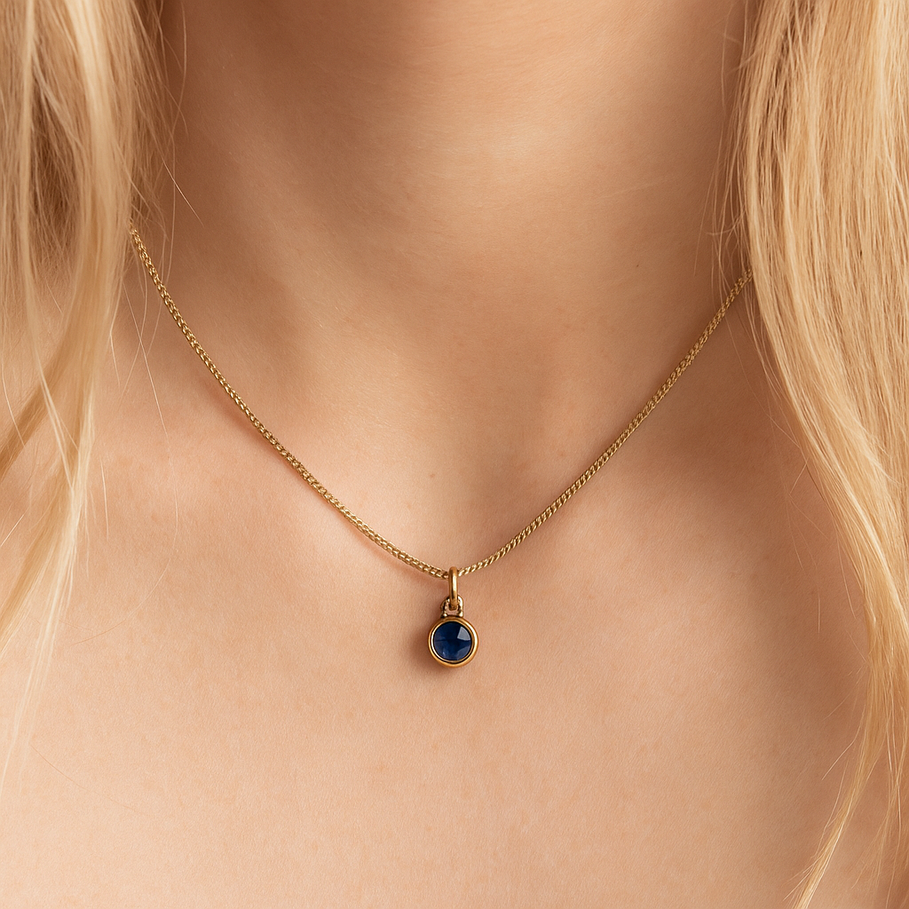 Gold necklace with a blue pendant on a person's neck